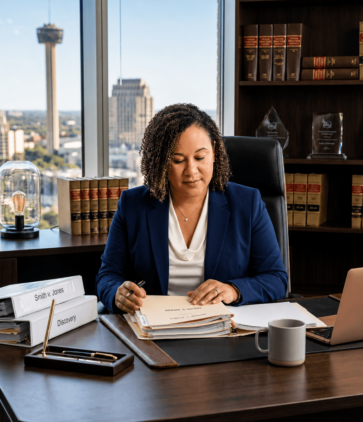 A female attorney reviews legal documents at a desk overlooking the San Antonio skyline.